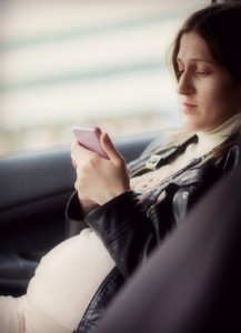Young pregnant woman chatting on the cellphone while sitting in the car
